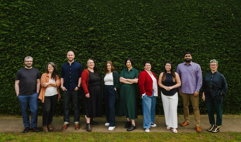 Quiip team standing against a hedge.